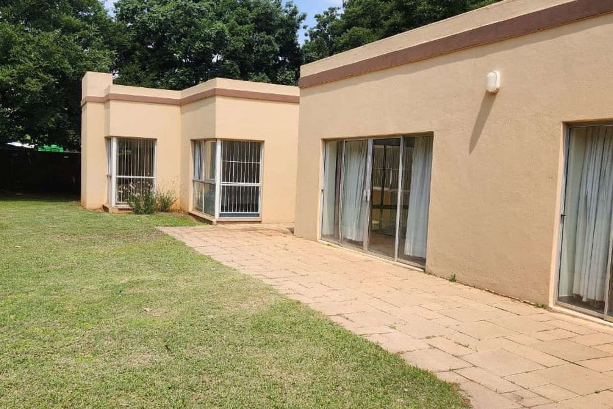 Rear view of the property featuring a paved patio area, sliding glass doors with security bars, and access to the garden.