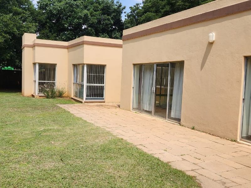 Rear view of the property featuring a paved patio area, sliding glass doors with security bars, and access to the garden.