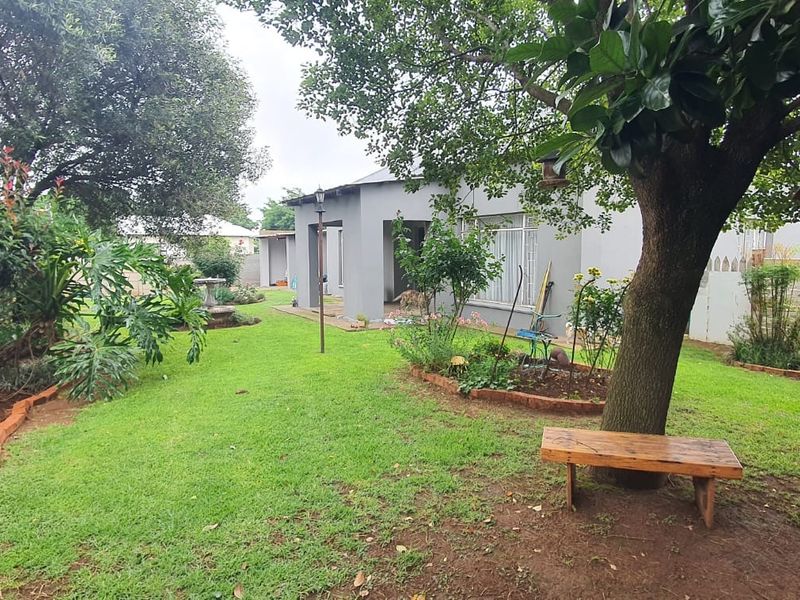 A well-maintained rear garden featuring a lush lawn, mature trees, and concrete boundary walls, providing a private outdoor space.