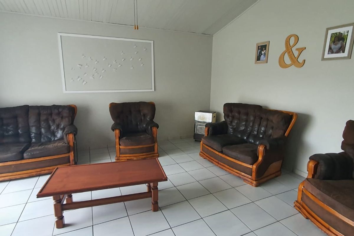 A living room featuring tiled flooring and a tongue and groove ceiling, providing a functional and neutral space for relaxation.
