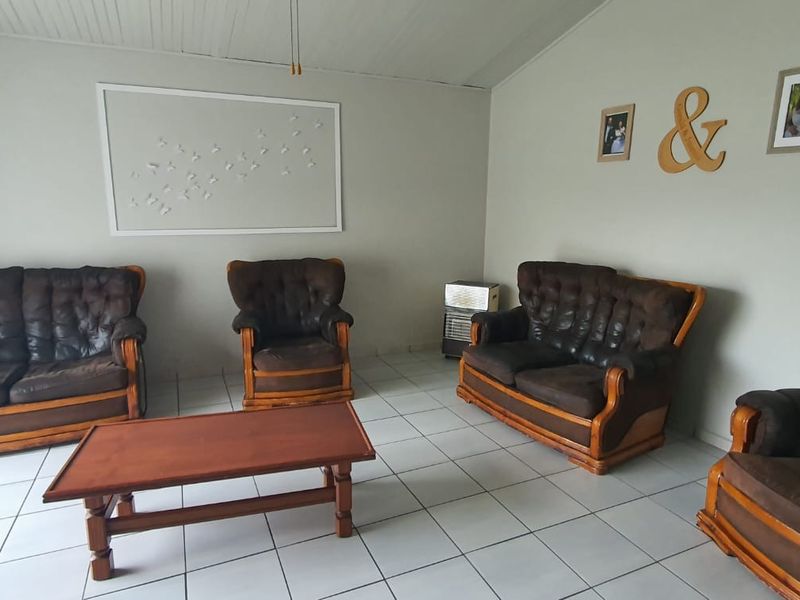 A living room featuring tiled flooring and a tongue and groove ceiling, providing a functional and neutral space for relaxation.