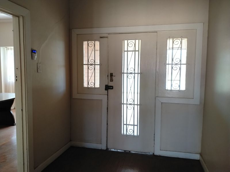Entrance foyer featuring a traditional timber door with integrated security grilles and original architectural trim.