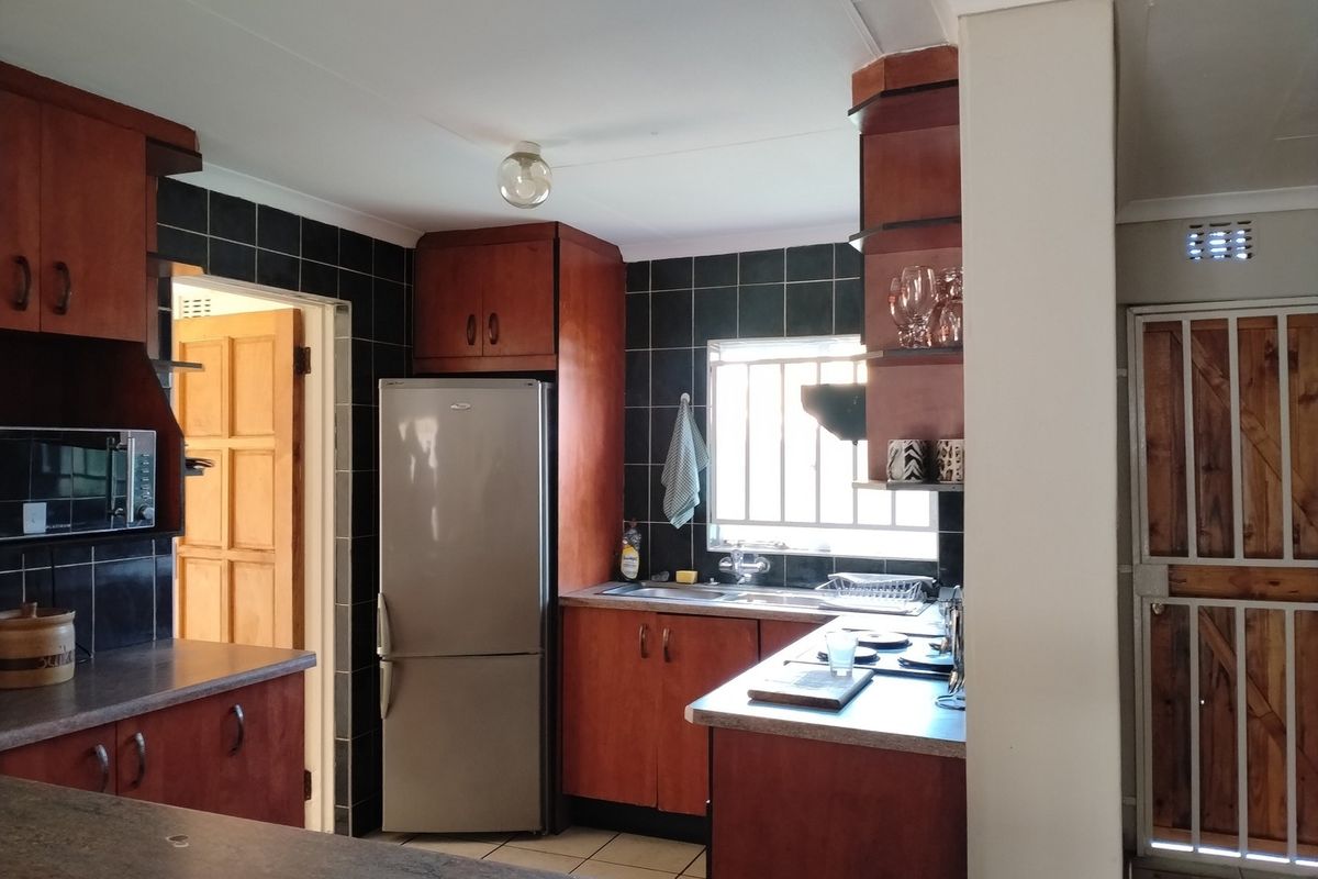 A functional kitchen featuring dark wood cabinetry, laminate countertops, a tiled backsplash, and a built-in oven, offering a classic layout with potential for modernization.