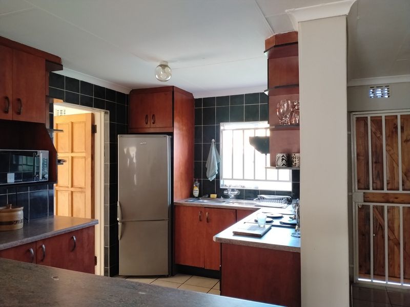 A functional kitchen featuring dark wood cabinetry, laminate countertops, a tiled backsplash, and a built-in oven, offering a classic layout with potential for modernization.