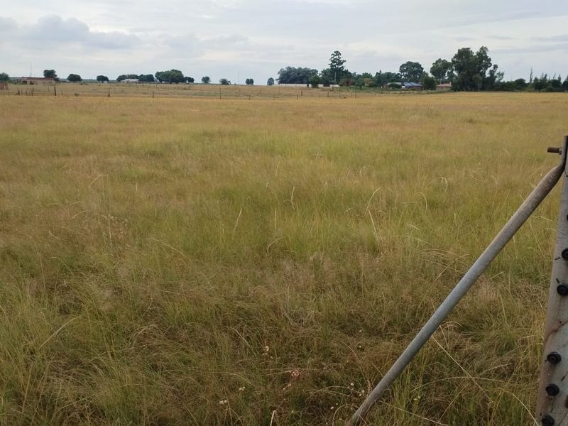 Expansive open land area featuring perimeter electric fencing, suitable for agricultural use or future development on this small holding.
