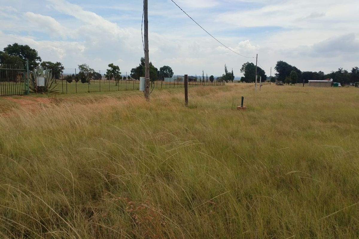 Expansive open land area featuring perimeter fencing and utility infrastructure, suitable for agricultural or development purposes on this small holding.
