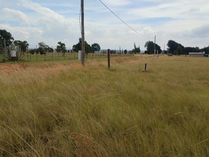 Expansive open land area featuring perimeter fencing and utility infrastructure, suitable for agricultural or development purposes on this small holding.