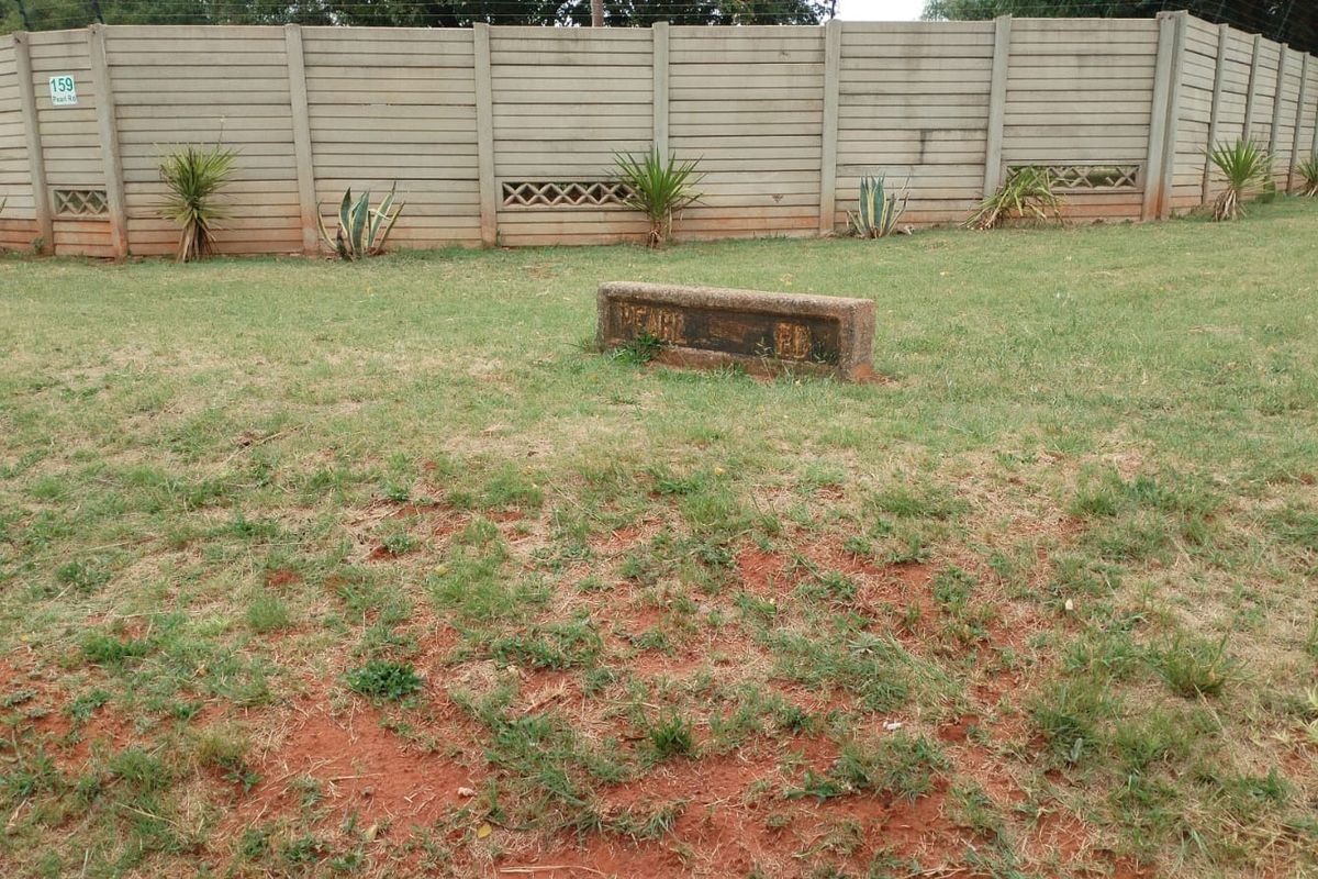 A view of the property garden featuring a secure precast concrete boundary wall and a small concrete signage plinth.