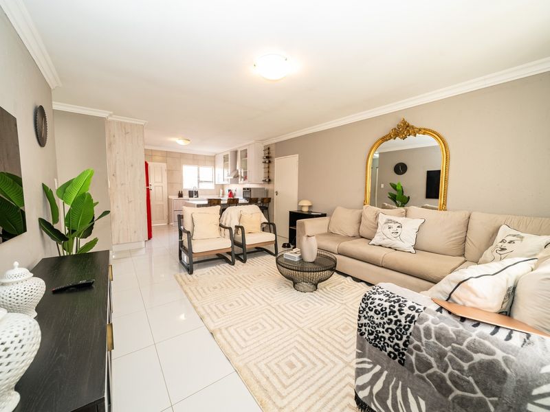 An open-plan living area featuring tiled flooring and a seamless transition into a functional kitchen space with built-in cabinetry and an island.