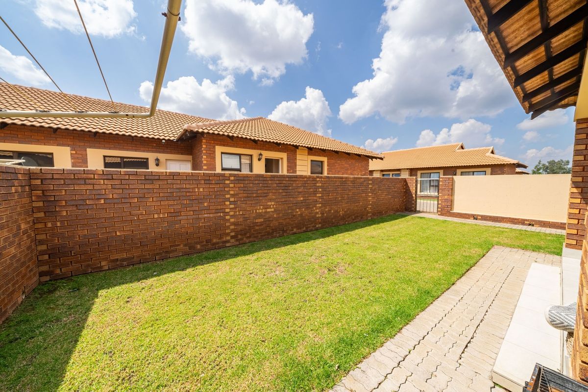 A private rear garden featuring a well-maintained lawn, paved pathway, and secure brick boundary walls, providing a functional outdoor space for the townhouse.