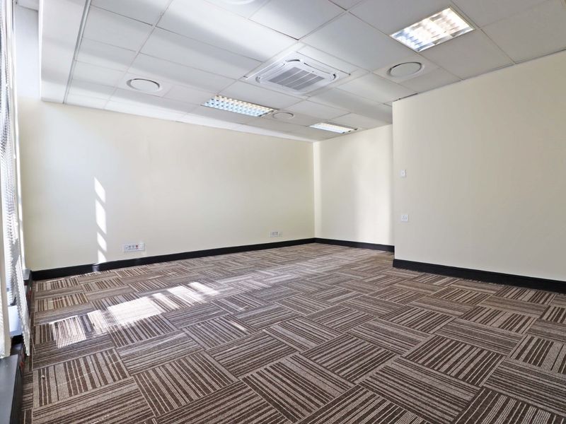 A clean, vacant office space featuring carpet tiles, suspended ceilings with recessed lighting, and integrated air conditioning, ready for immediate professional use.