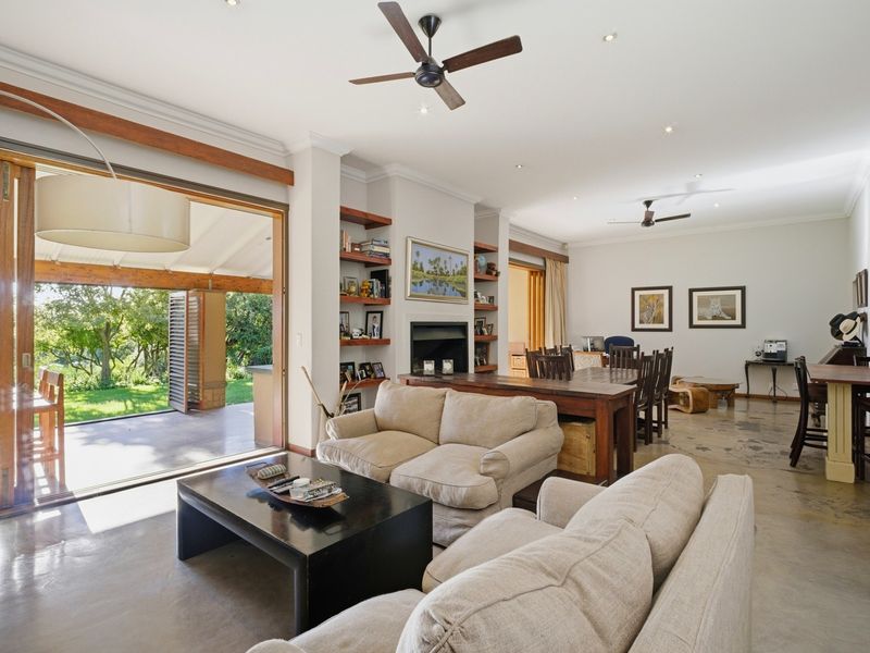 Spacious open-plan living and dining area featuring polished concrete floors, a fireplace with built-in shelving, and large sliding doors opening to a patio.