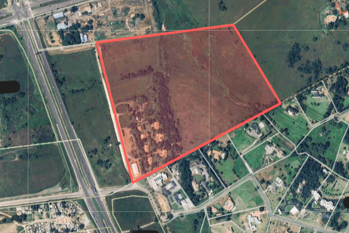 Aerial view of a large farm property parcel highlighted in red, showing surrounding road infrastructure and neighbouring land plots.