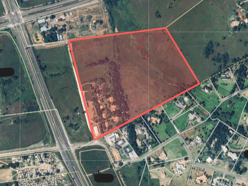 Aerial view of a large farm property parcel highlighted in red, showing surrounding road infrastructure and neighbouring land plots.