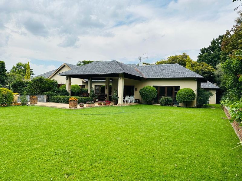 Rear view of the townhouse featuring a spacious lawn, a covered patio area, and well-maintained garden landscaping.