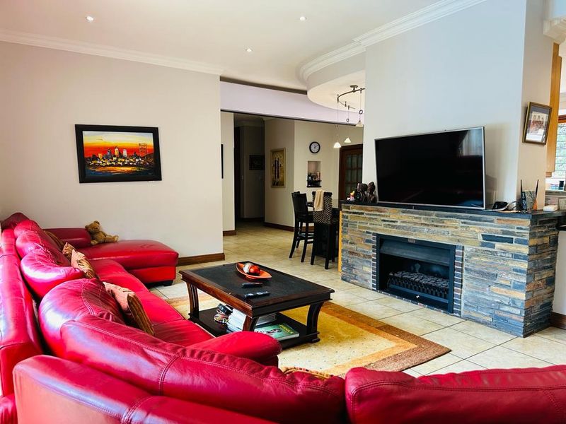 Spacious living room featuring a prominent stone-clad fireplace, tiled flooring, and recessed lighting, creating a comfortable and functional central living area.
