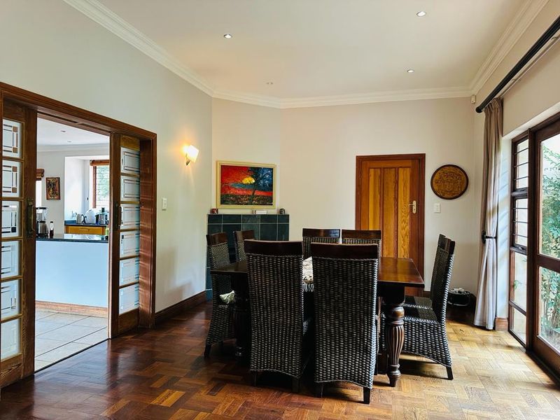 A well-maintained dining room featuring classic parquet flooring, elegant cornicing, and sliding wooden doors that provide access to the adjacent kitchen area.