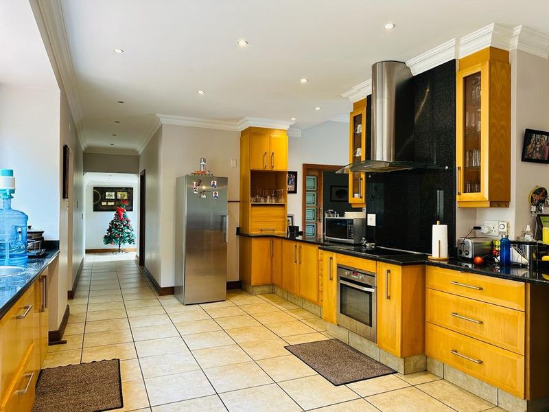 A spacious kitchen featuring wooden cabinetry, granite countertops, stainless steel appliances, and tiled flooring, with recessed lighting and crown molding throughout.