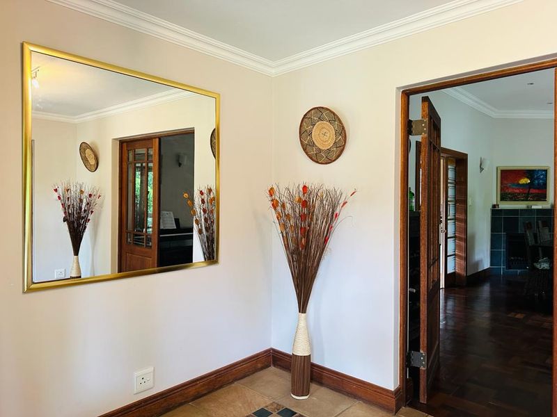A well-maintained hallway featuring crown molding, tiled flooring, and classic wooden door frames leading into adjacent living spaces.