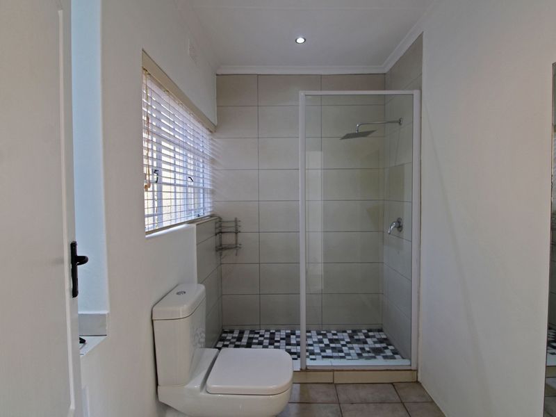 A clean, modern bathroom featuring a walk-in shower with a glass screen, tiled walls, and a neutral color palette.