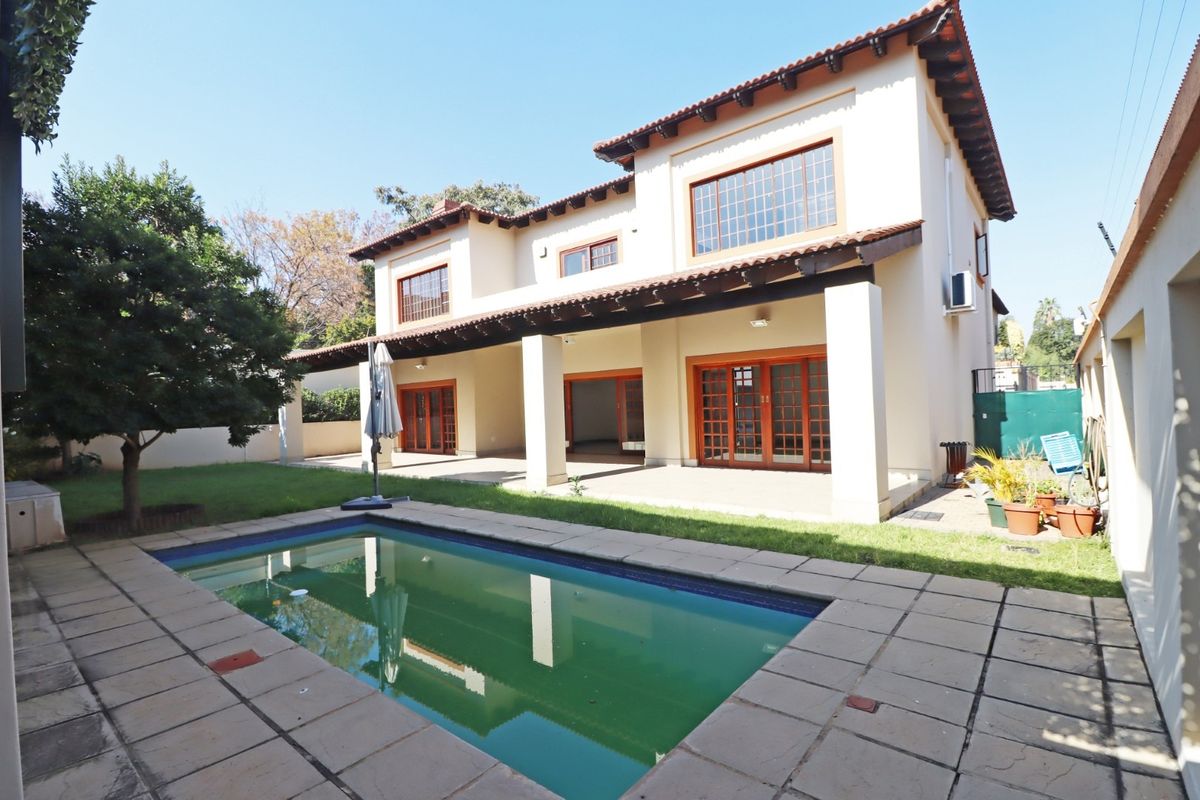 Rear view of the house featuring a covered patio, swimming pool, and paved outdoor area, ideal for entertaining.