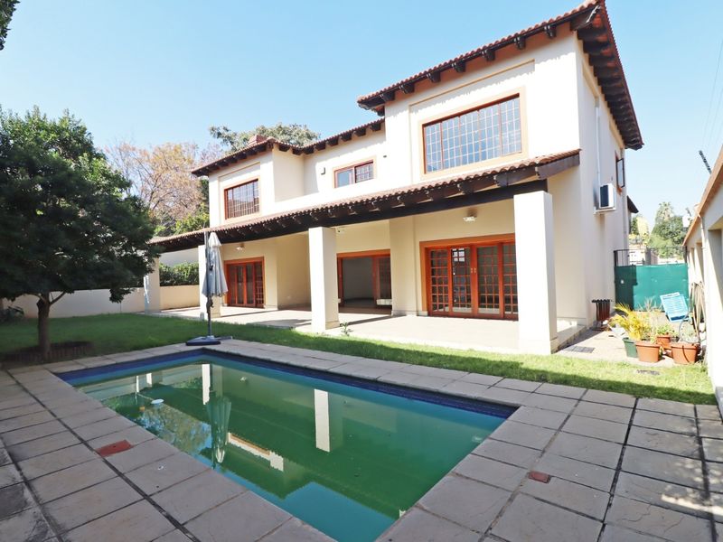 Rear view of the house featuring a covered patio, swimming pool, and paved outdoor area, ideal for entertaining.