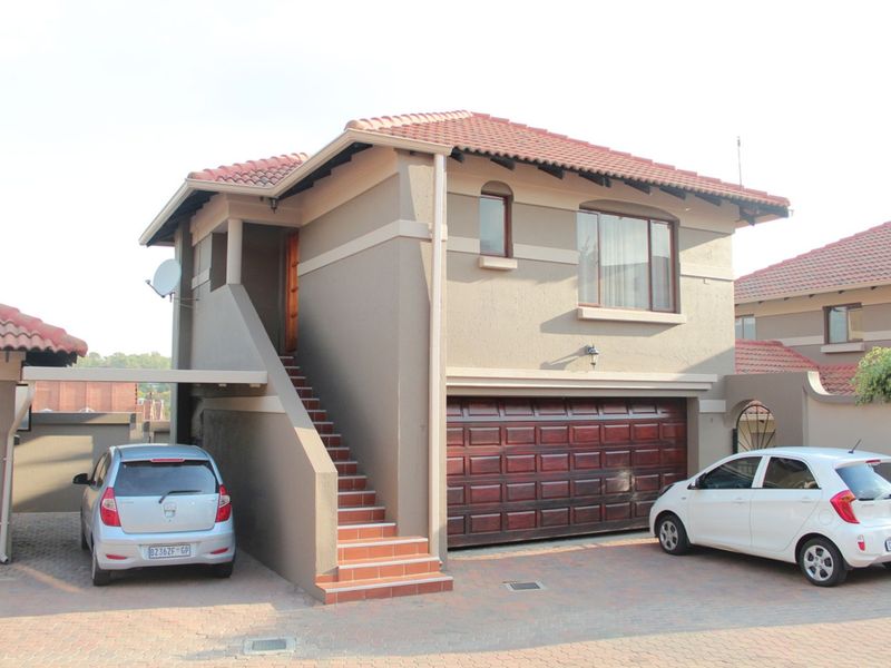 Front view of a double-story apartment unit featuring a tiled roof, a wooden sectional garage door, and an external staircase leading to the upper level.