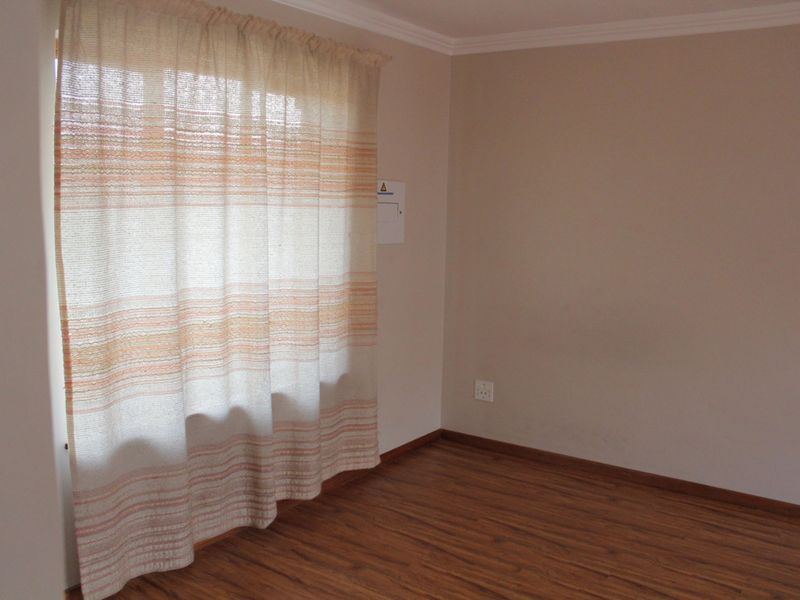A vacant bedroom featuring laminate wood flooring, neutral wall paint, and decorative coving, providing a clean and versatile space ready for personalization.