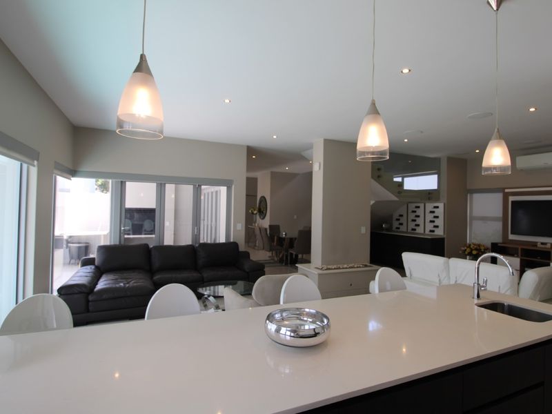 Spacious open-plan living area featuring a modern kitchen island with quartz countertops, pendant lighting, and seamless flow to the outdoor patio through sliding doors.