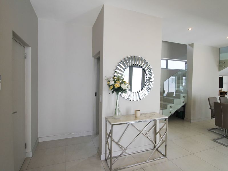 Modern entrance hall featuring tiled flooring, recessed lighting, and a contemporary glass balustrade staircase leading to the upper level.