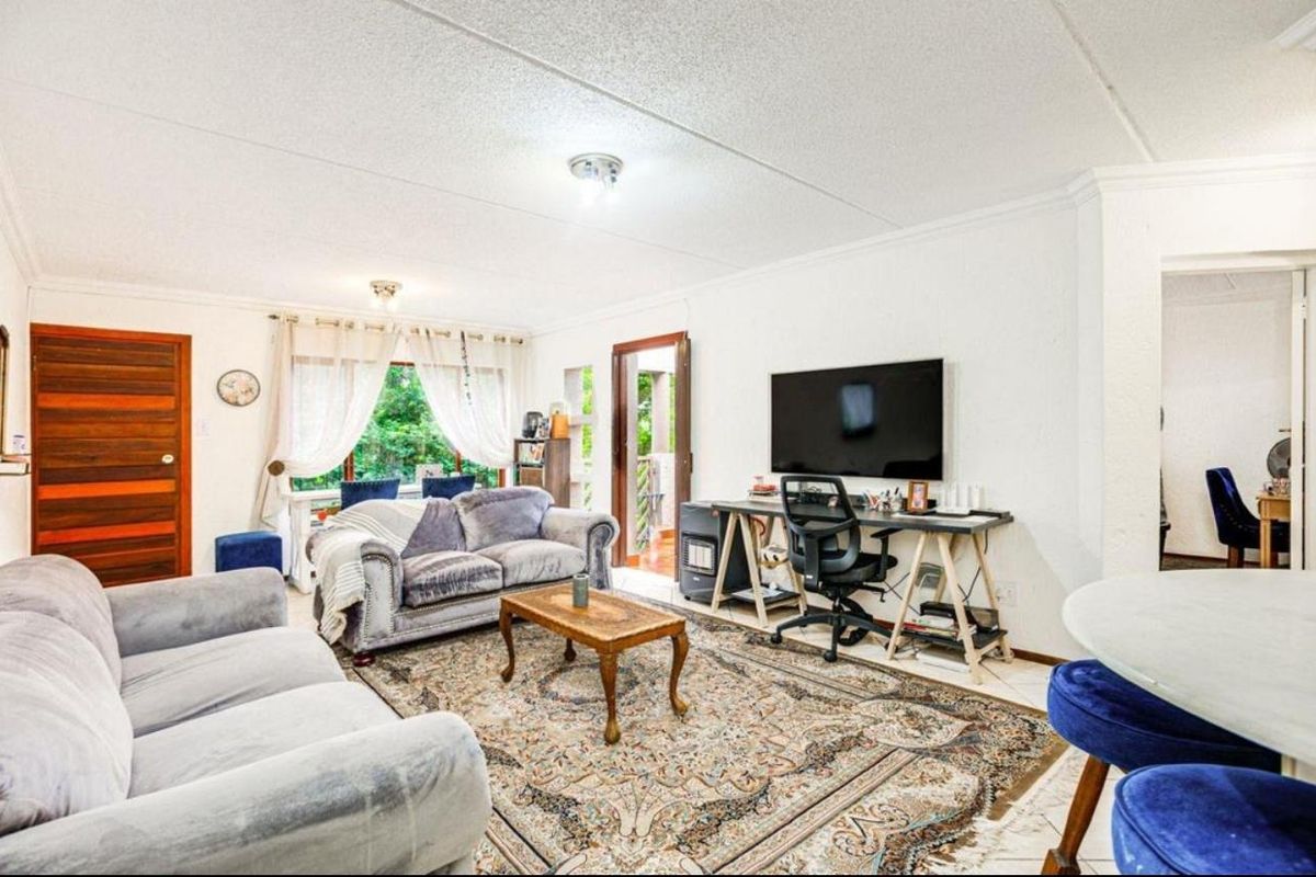 A spacious living room featuring tiled flooring, textured ceilings, and direct access to an outdoor area through a sliding door.