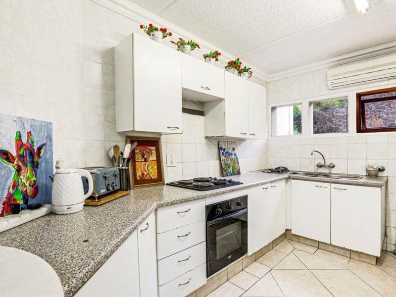 Functional kitchen featuring white cabinetry, granite countertops, built-in oven, gas hob, and tiled finishes, offering a practical layout for daily cooking.