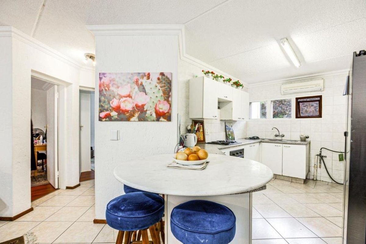 A functional kitchen featuring white cabinetry, tiled flooring, and a built-in cooktop, offering a practical layout with potential for modern updates.