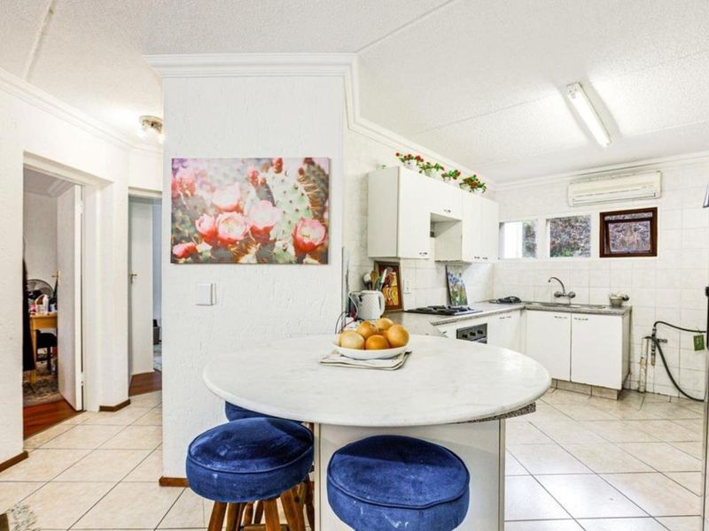 A functional kitchen featuring white cabinetry, tiled flooring, and a built-in cooktop, offering a practical layout with potential for modern updates.