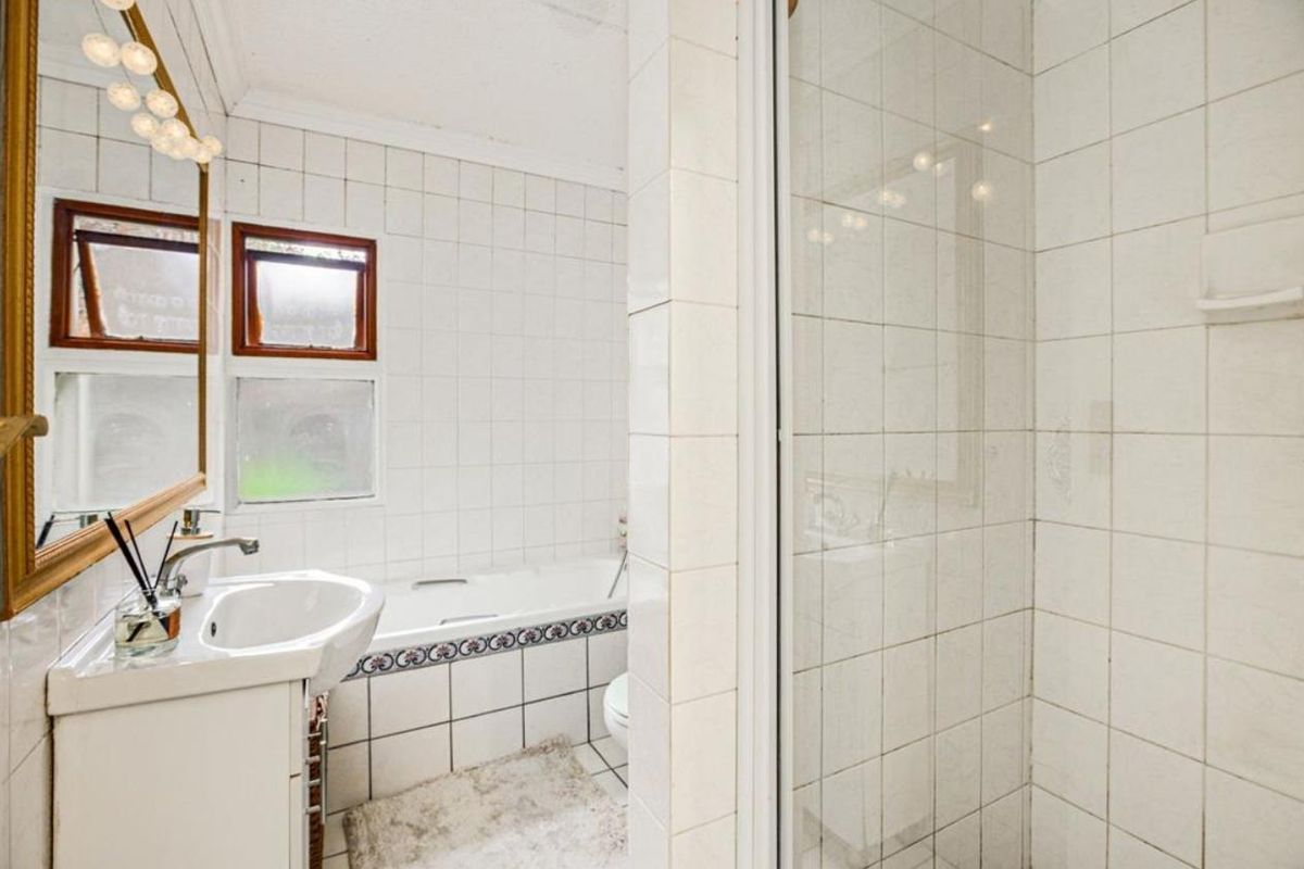 A functional bathroom featuring a built-in bathtub, separate shower enclosure, and pedestal basin with classic white wall tiling.