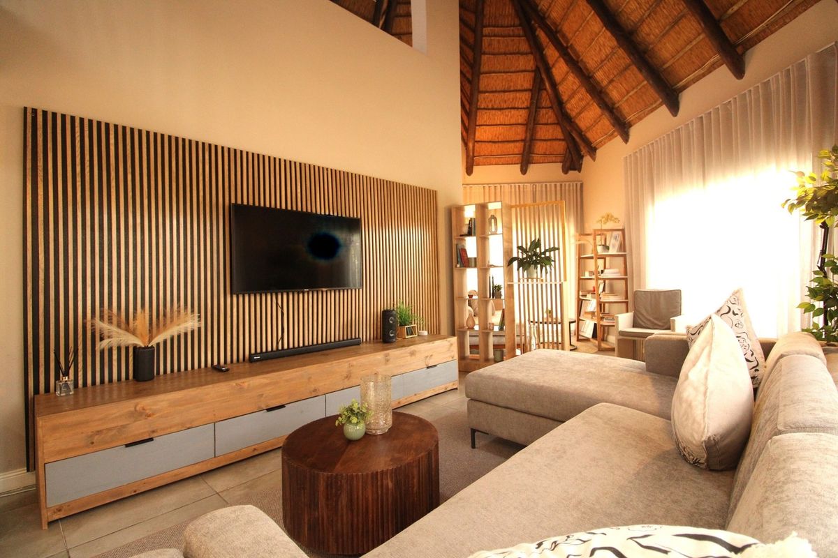 Spacious living room featuring a high thatched ceiling with exposed rafters, a modern timber slat feature wall, and a built-in media console.