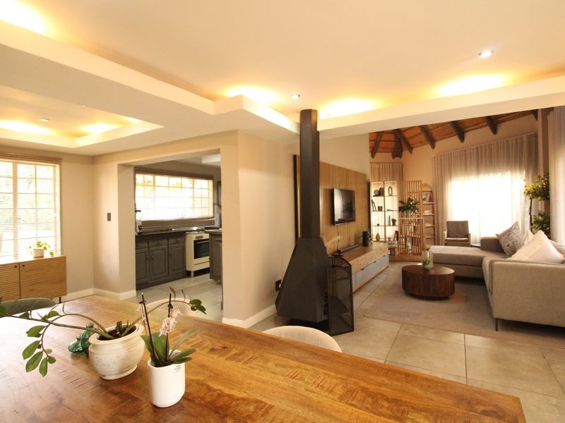 Spacious open-plan living area featuring a modern freestanding fireplace, recessed ceiling lighting, tiled floors, and a seamless transition to the kitchen and dining space.