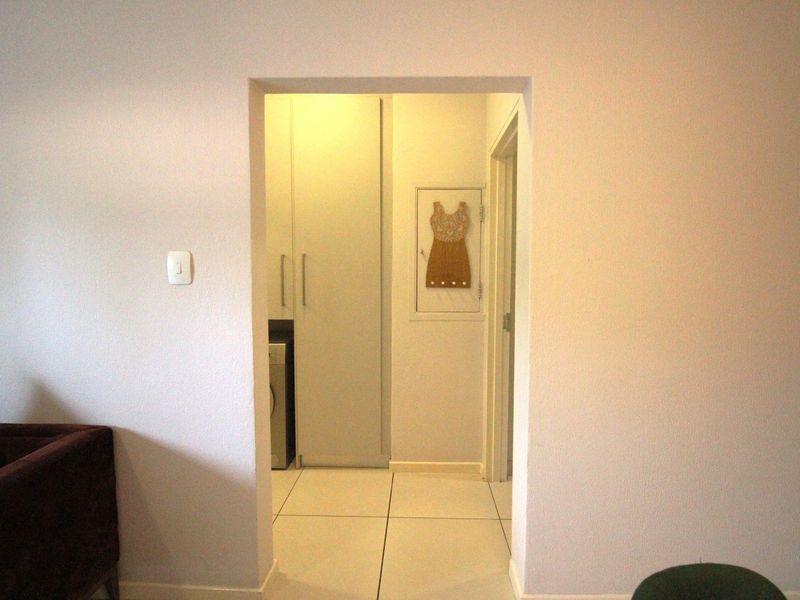 A functional laundry area featuring built-in cabinetry and clean tiled flooring, accessible through a doorway from the main living space.