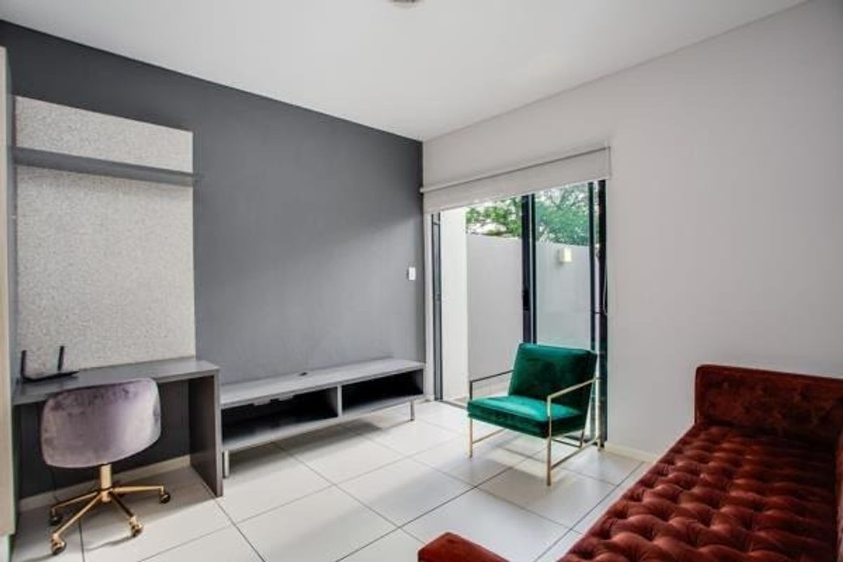 A modern living area featuring tiled floors, a built-in desk, a media console, and a sliding glass door leading to an outdoor space.