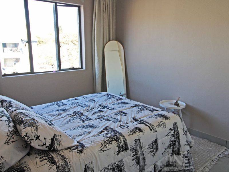 A functional bedroom featuring tiled flooring and a large window allowing for natural light.