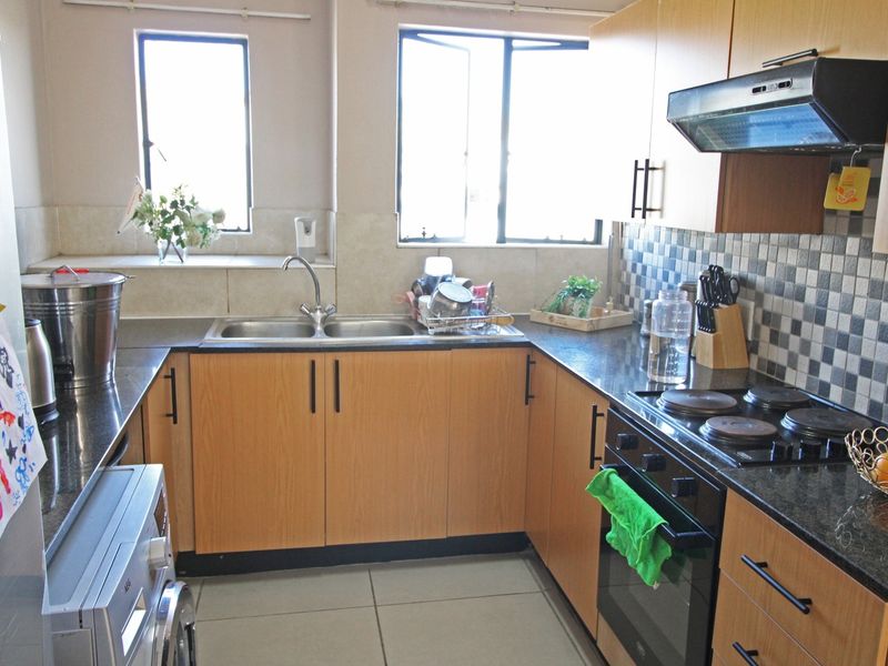 Functional kitchen featuring laminate cabinetry, granite countertops, a double bowl sink, built-in oven, electric hob, and extractor fan with tiled splashback.