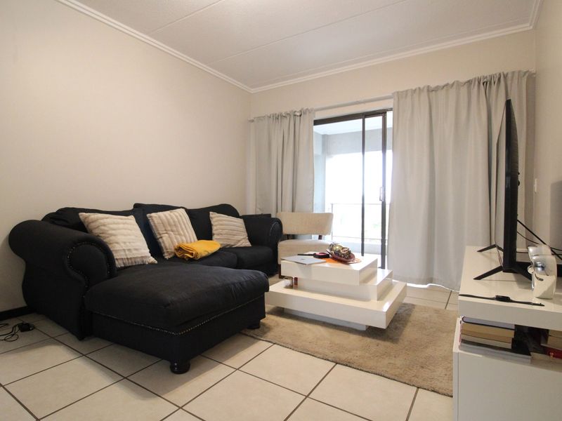 A comfortable living room featuring tiled flooring and a sliding glass door that provides access to an outdoor balcony area.