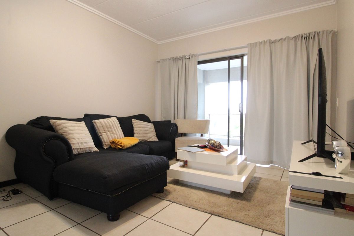 A comfortable living room featuring tiled flooring and a sliding glass door that provides access to an outdoor balcony area.