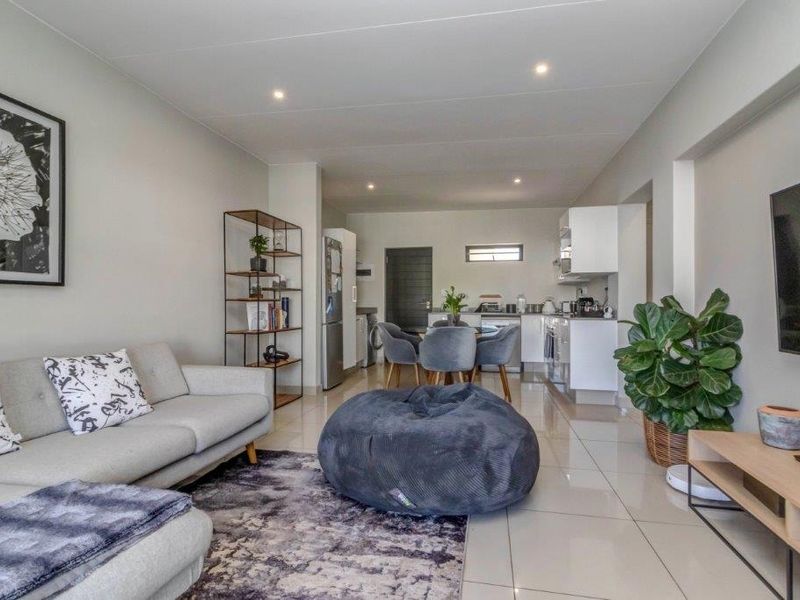 Modern open-plan living area featuring tiled floors, recessed lighting, and a seamless transition into a functional kitchen space.