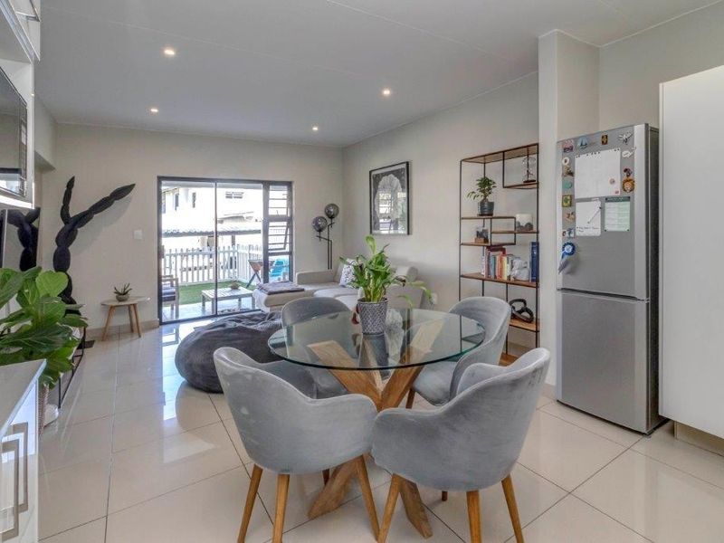 Bright open-plan living and dining area featuring modern tiled floors, recessed lighting, and seamless access to an outdoor patio through sliding glass doors.