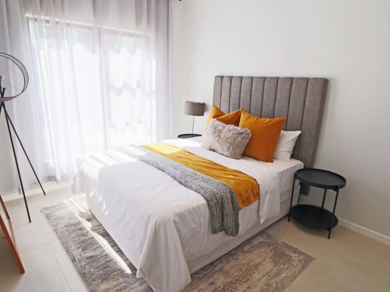 A bright and well-maintained bedroom featuring tiled flooring and a large sliding glass door that allows for ample natural light.