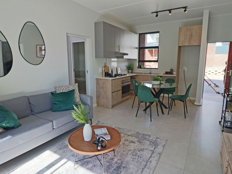 Modern open-plan living area featuring a contemporary kitchen with built-in cabinetry, integrated appliances, and sleek tiled flooring throughout.