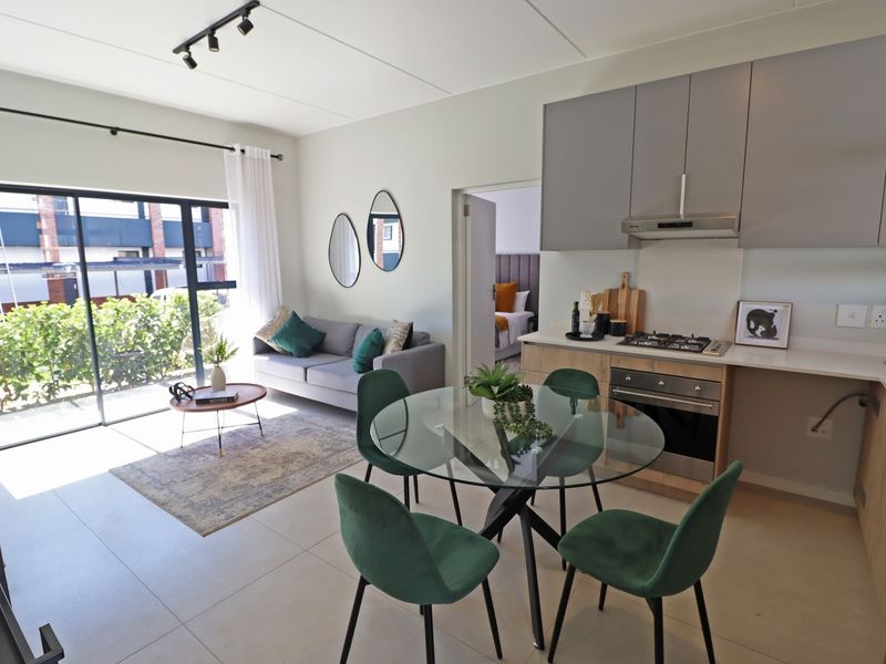 Modern open-plan living area featuring a contemporary kitchen with built-in appliances and seamless access to an outdoor patio through sliding glass doors.