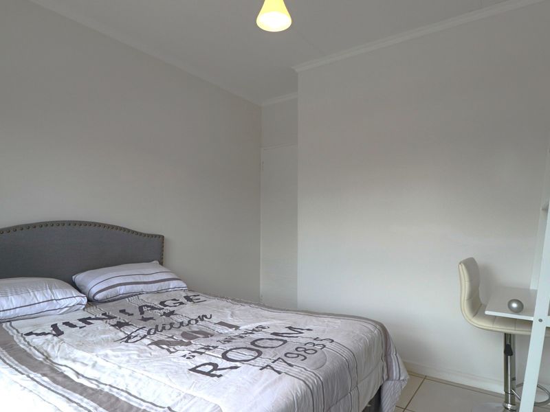 A simple bedroom featuring tiled flooring and neutral wall finishes, providing a functional space for rest.
