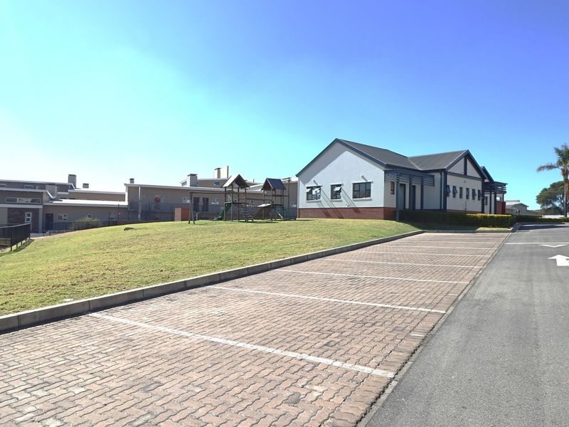 Exterior view of the apartment complex featuring a paved parking area, landscaped lawn, and well-maintained building facades under a clear sky.